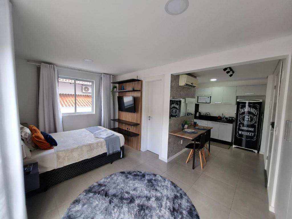 a bedroom with a bed and a small kitchen at Zu Hause, sua casa em Blumenau in Blumenau