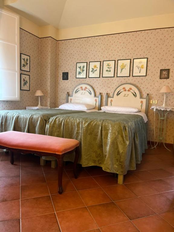 two beds in a room with a table and a bench at Villa Solarola Country House in Castel Guelfo di Bologna