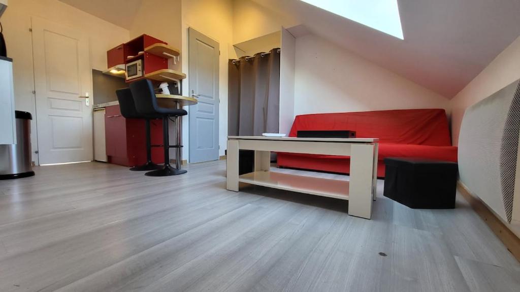 - un salon avec un canapé rouge et un bureau dans l'établissement joli petit T2 proche gare et centre, à Amiens