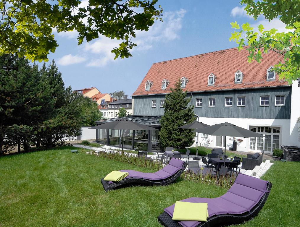 un hotel con sillas y mesas púrpuras en el césped en Hotel Maucksches Gut, en Freiberg