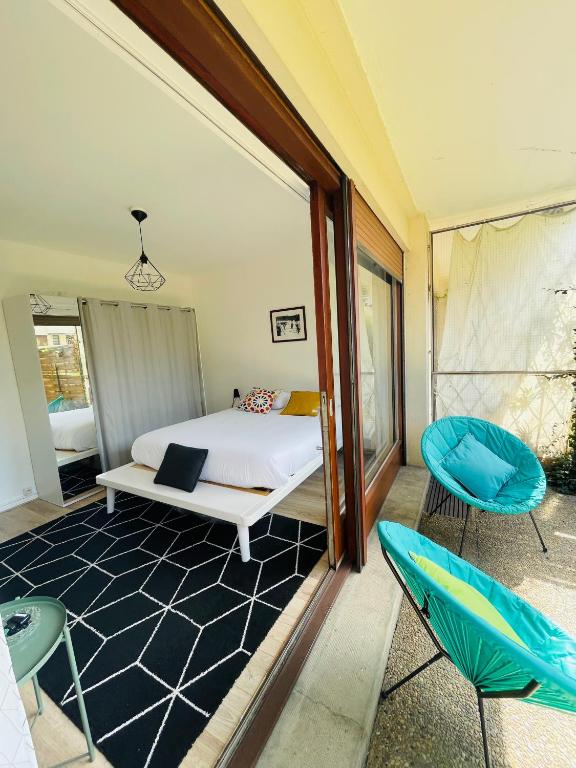 une chambre avec un lit et deux chaises dans l'établissement le Nid des Cèdres, voisin des Thermes et du centre, à Thonon-les-Bains