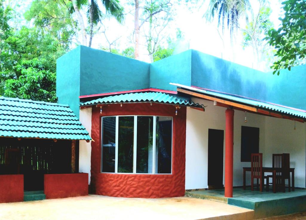 a small house with a blue roof at Dramatic Green Cottage in Udawalawe
