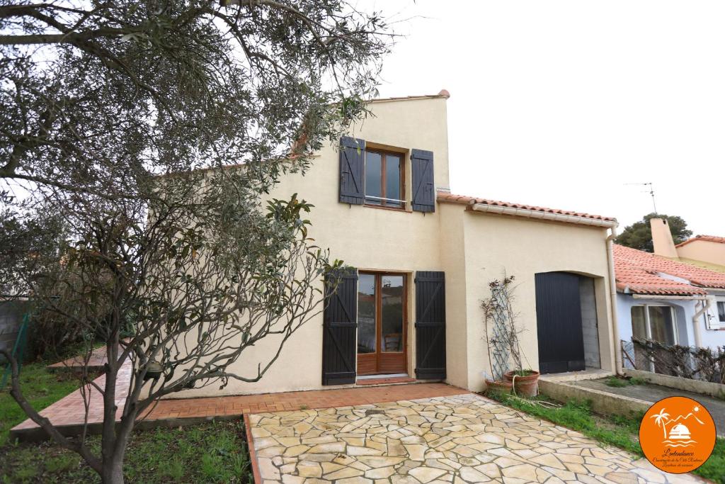 une maison avec un arbre devant dans l'établissement St Cyprien grande maison familiale proche plage, à Saint-Cyprien