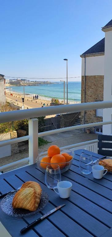 - une table avec du pain et des oranges sur un balcon donnant sur la plage dans l'établissement la perle de lecume, à Quiberon