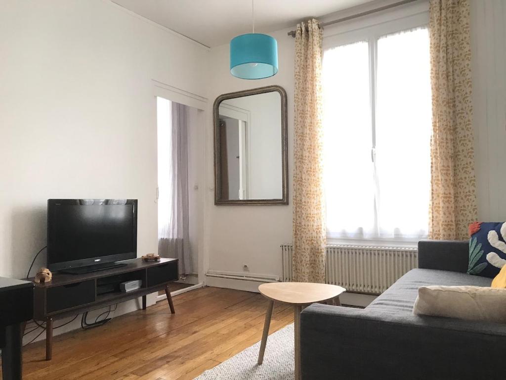 un salon avec un canapé et une télévision à écran plat dans l'établissement Charming 3-room apartment, Paris center, à Paris
