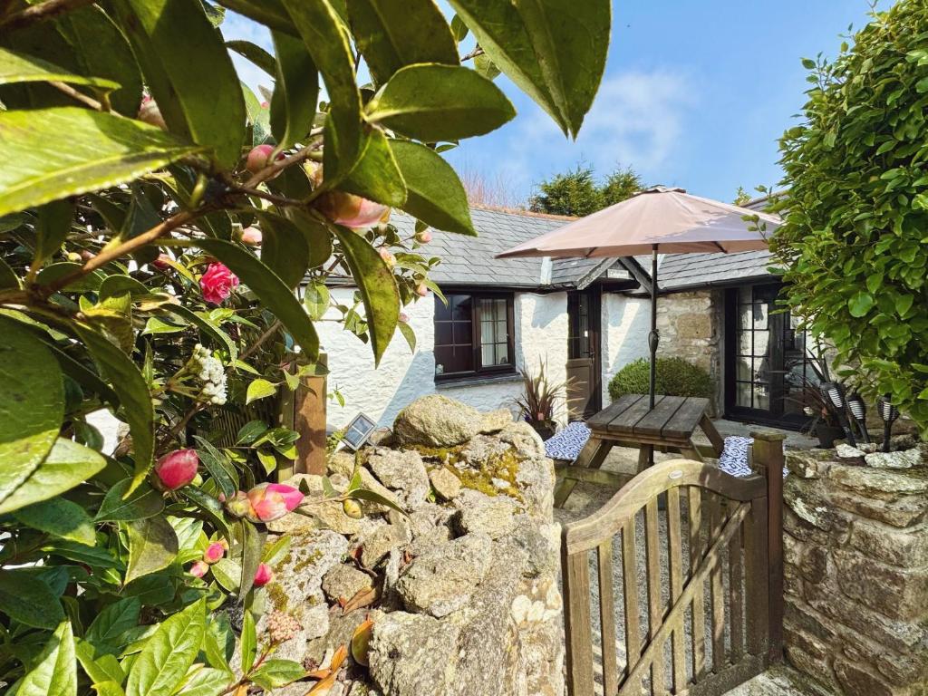 un cottage con recinzione, tavolo e ombrellone di Hallagenna Cottages a Bodmin