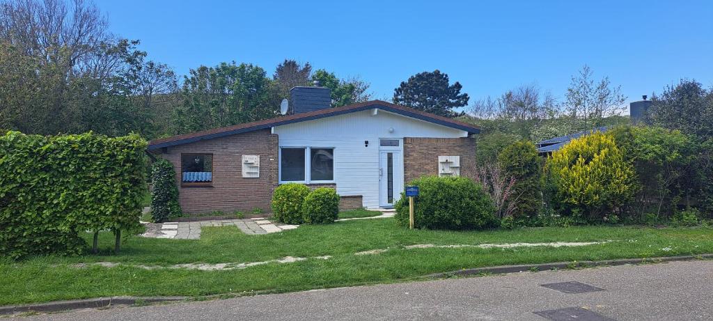a small house in a yard with a grass yard at Bungalow Marita in Julianadorp