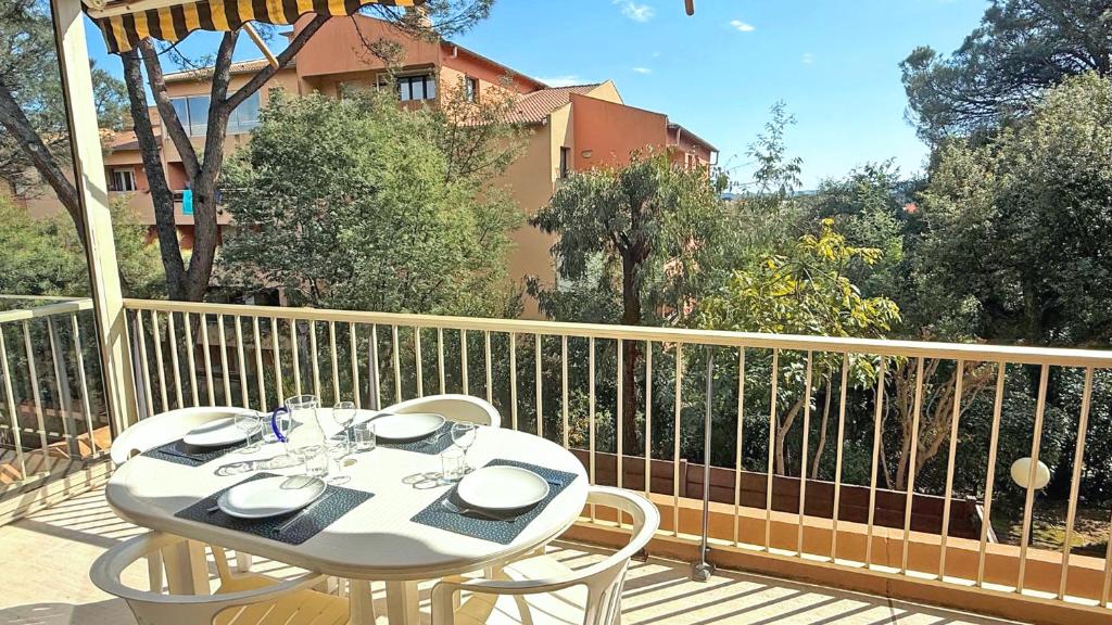 une table blanche et des chaises sur un balcon dans l'établissement Bosquets, à Sainte-Maxime