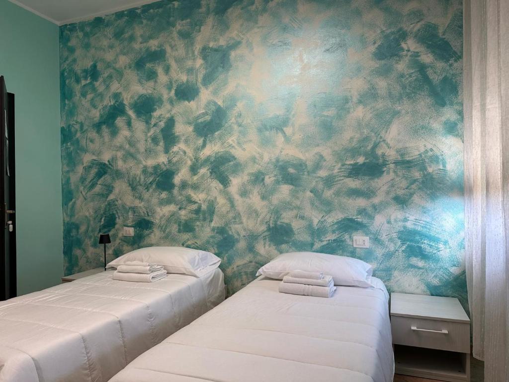 two beds in a room with a mural at Locanda San Martino in Collecchio