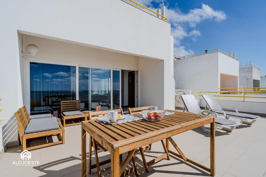 a patio with a wooden table and chairs on a balcony at Ericeira Panoramic Sea View Apartments in Ericeira