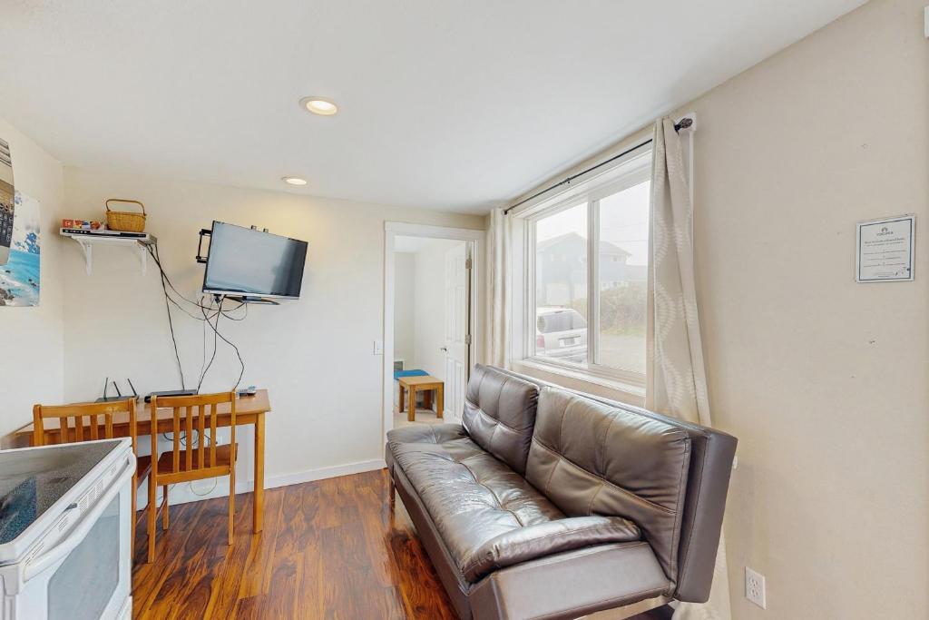 a living room with a leather couch and a window at Starfish 4 in Rockaway Beach