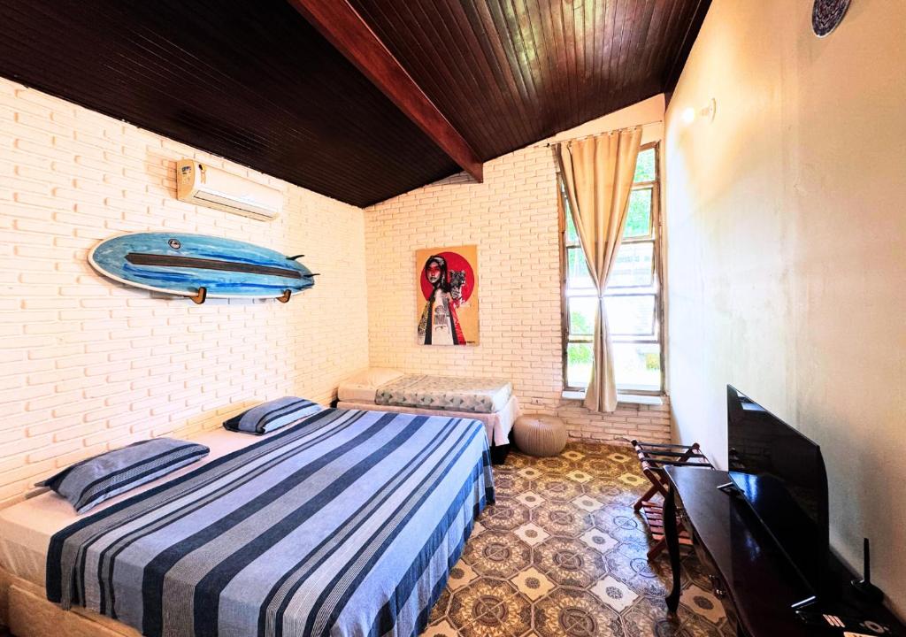 a bedroom with a bed and a surfboard on the wall at Tombo Beach Home Stay in Guarujá
