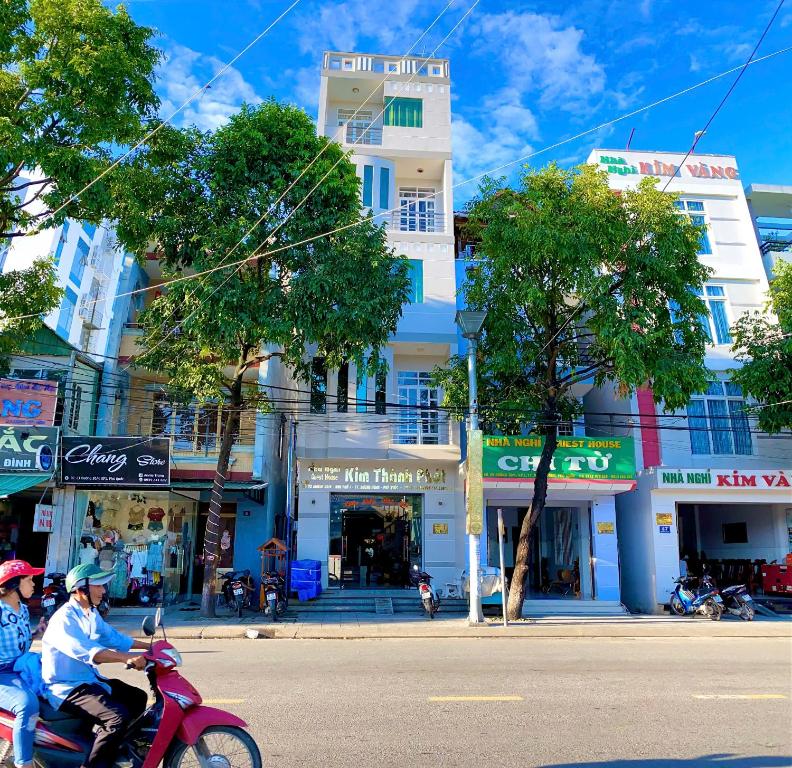 dos personas montando un scooter rojo por una calle de la ciudad en Kim Thành Phát guest house, en Phu Quoc