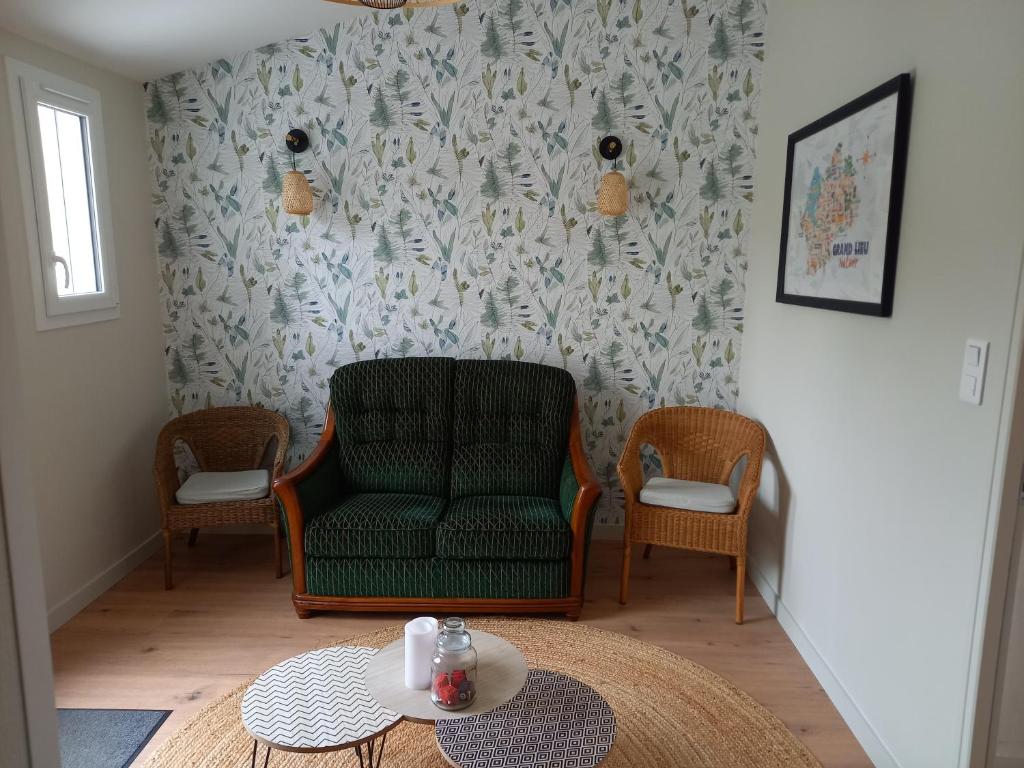 a living room with a green chair and two chairs and a table at Gite les demoiselles in Saint-Lumine-de-Coutais