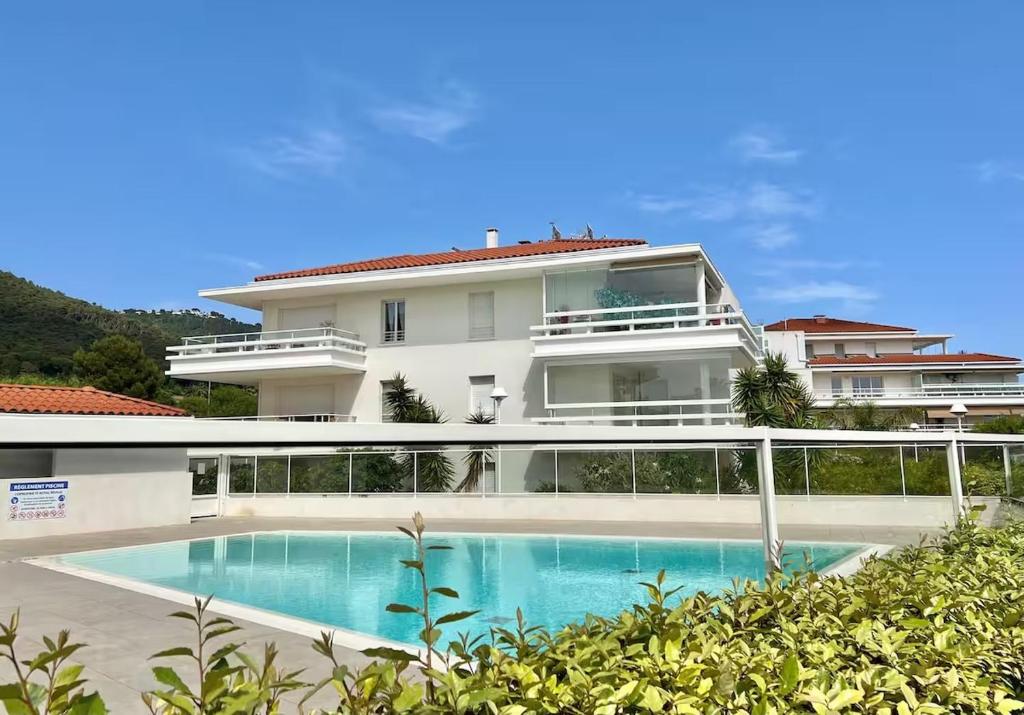 - un grand bâtiment blanc avec une piscine en face dans l'établissement Royal Rivage - Piscine - Mer à 200m, à Carqueiranne