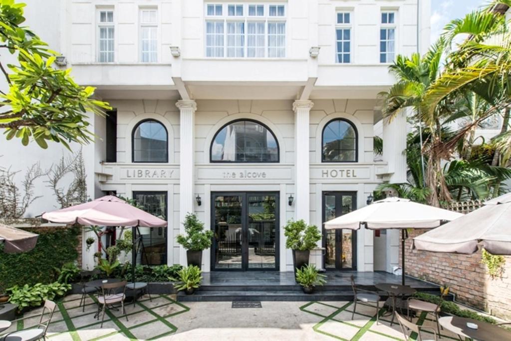 a hotel with tables and umbrellas in front of it at The Alcove Library Hotel in Ho Chi Minh City