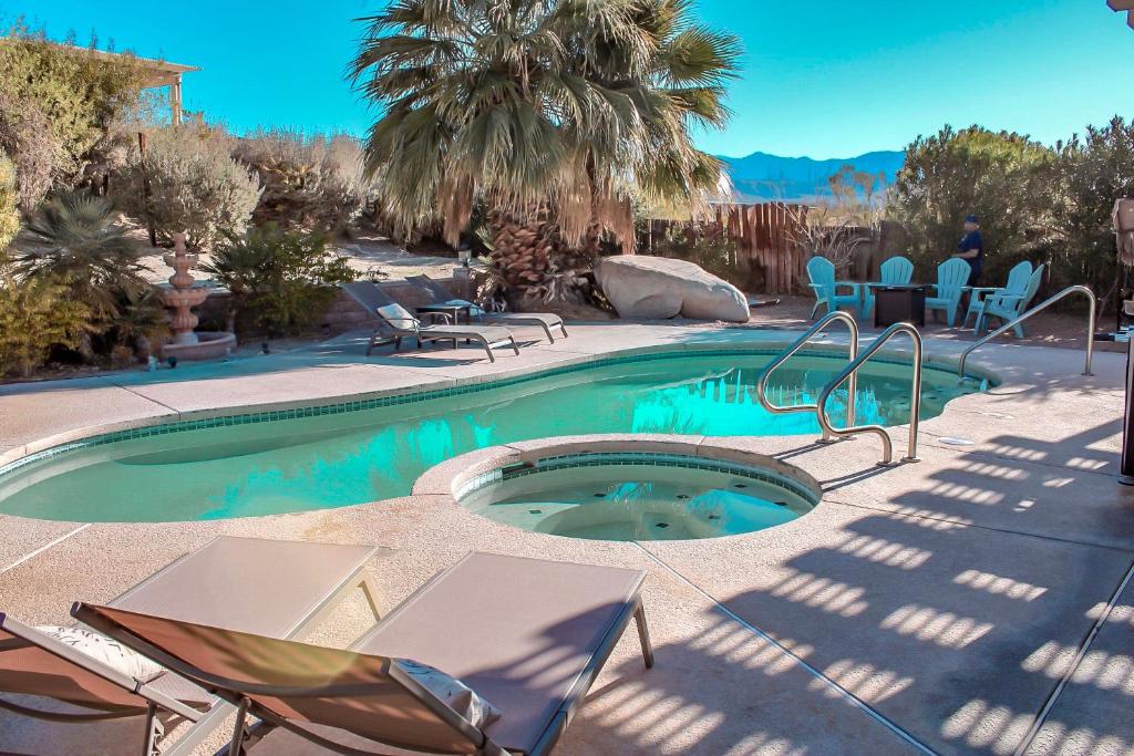 a swimming pool with chairs and a table and chairs at Poolside Oasis with Game Room in Desert Hot Springs! in Desert Hot Springs