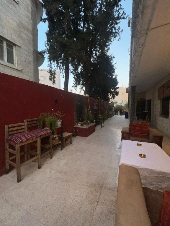 a courtyard with benches and a red wall at bayt alrahaal in Amman