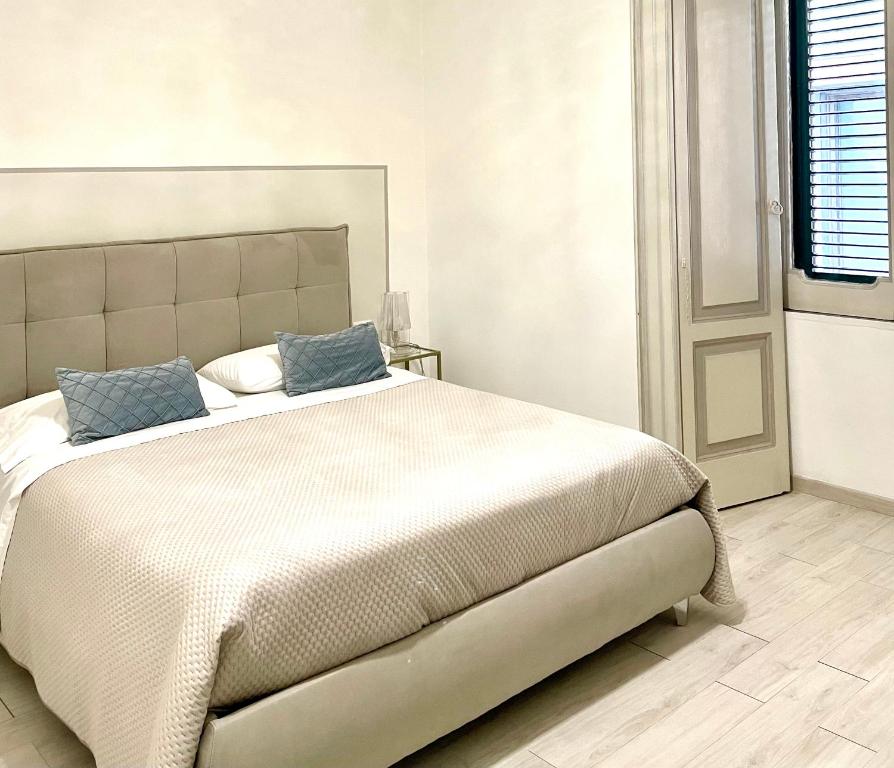 sypialnia z dużym białym łóżkiem i niebieskimi poduszkami w obiekcie Salerno Center House - Corso Vittorio Emanuele w mieście Salerno