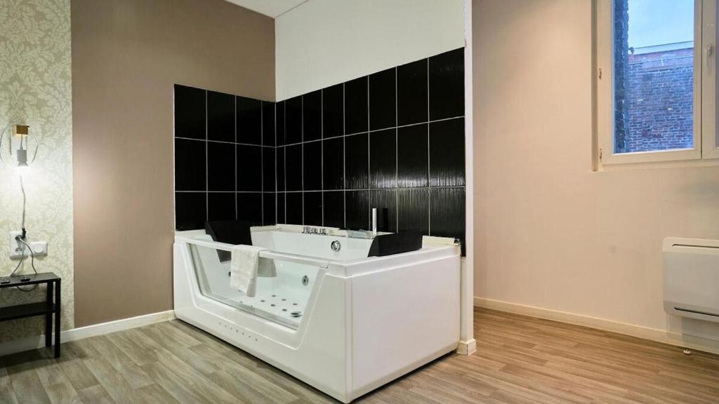 bagno con vasca bianca e parete piastrellata nera di Suite Beige #2#- Vue & jacuzzi privé-self check-in a Roubaix