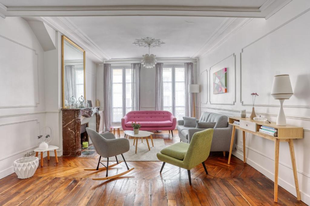 - un salon avec un canapé et des chaises roses dans l'établissement Le Colbert, à Versailles