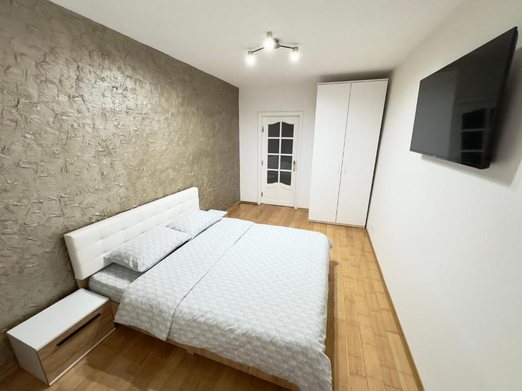 1 dormitorio con cama blanca y pared en Rusky Apartment, en Gura Humorului