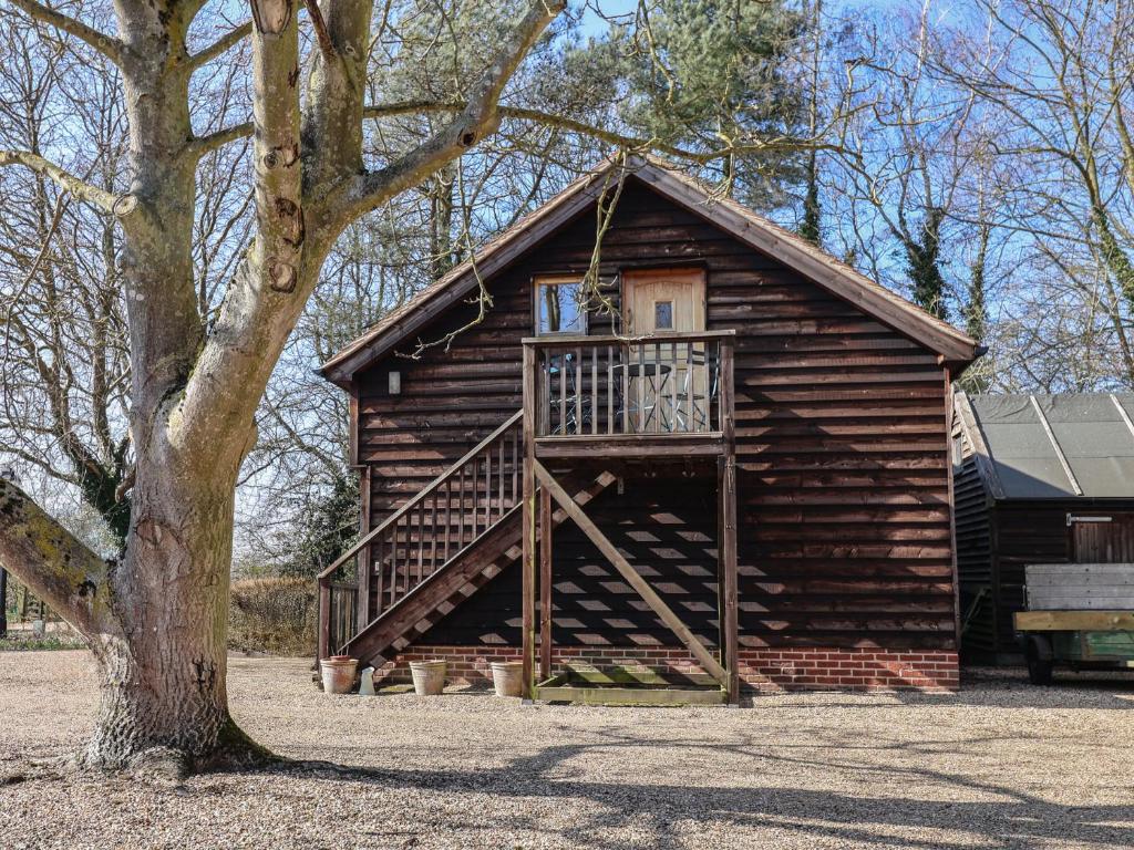 Cabaña de madera con balcón en un lateral. en Woodland Retreat Lodge, en Woodbridge