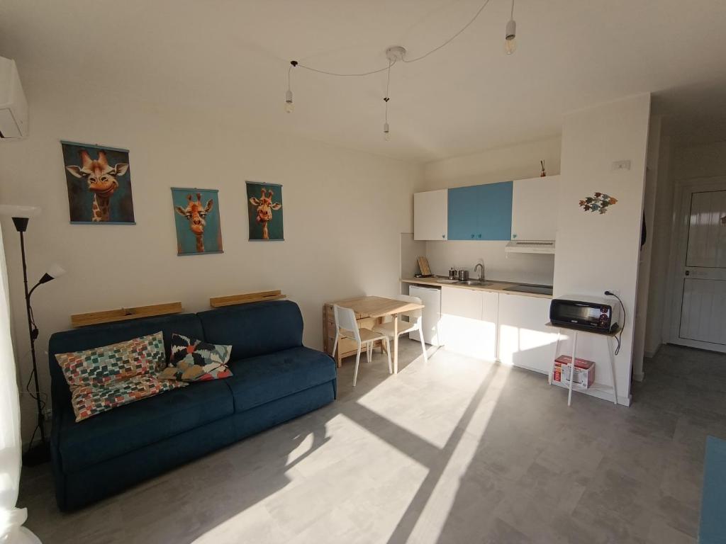 a living room with a blue couch and a kitchen at En Allusi Apartment in Badesi