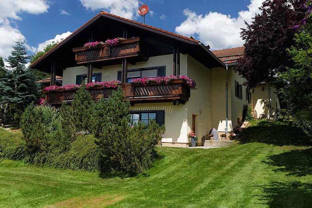 Una casa con flores en el balcón. en Ferienwohnung im Landhaus am Nationalpark en Ludwigsthal