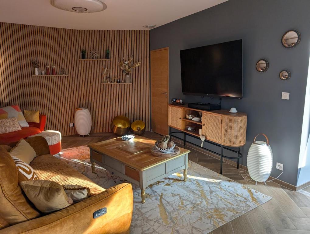 un salon avec un canapé et une télévision à écran plat dans l'établissement Maison tout confort entre terre et mer en Normandie, à Douvres-la-Délivrande