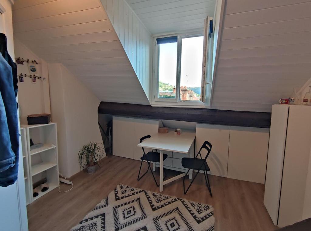 Cette petite chambre dispose d'une table et d'une fenêtre. dans l'établissement Studio centre ville Besançon - vue Citadelle, à Besançon