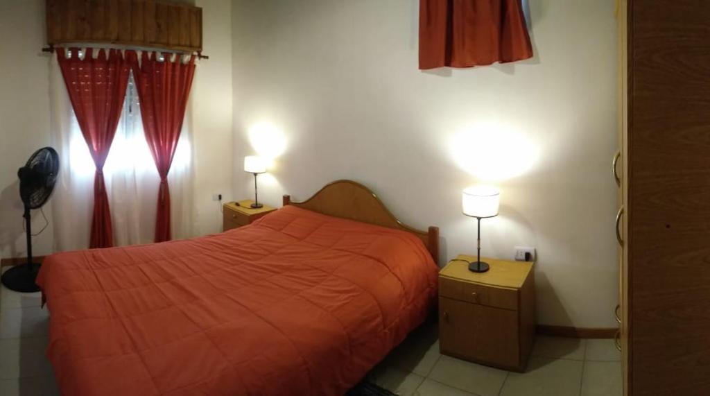 a bedroom with a red bed and two lamps at La casa de Yoni in Las Toninas