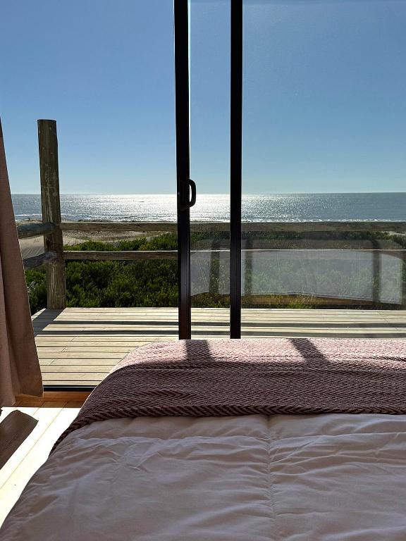 a bed in a room with a view of the ocean at Casa frente al mar Papaya Grande in Punta Del Diablo