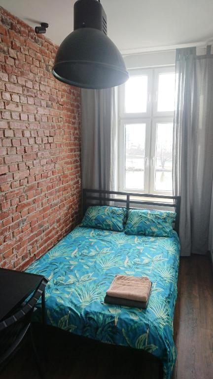 a bedroom with a bed and a brick wall at 9Wygodny pokoj w centrum Wroclawia in Wrocław