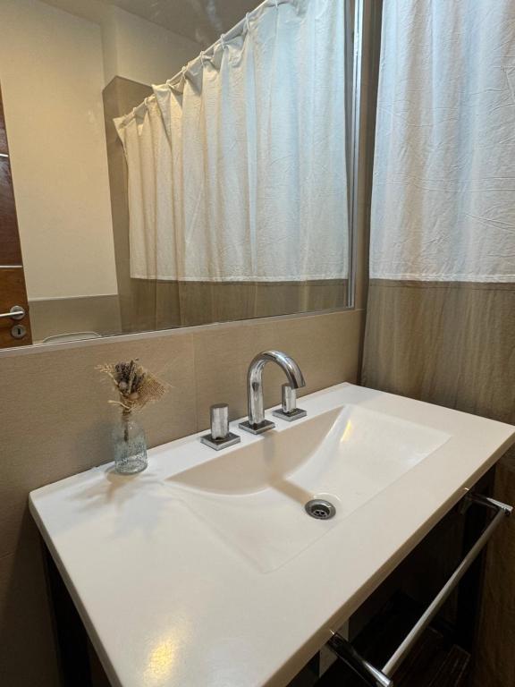 Un lavabo blanco en un baño con espejo. en Mi Ruca, en Puerto Madryn