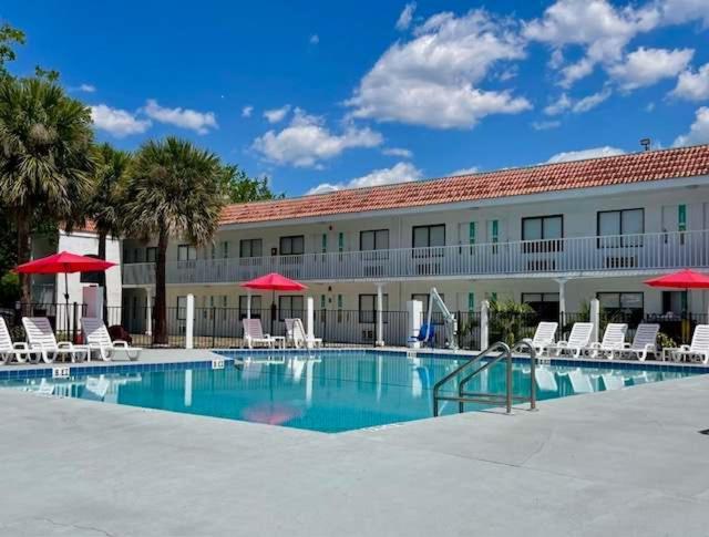 a hotel with a swimming pool with chairs and umbrellas at Impeccably cozy hotel room Developer Inn Express in Kissimmee