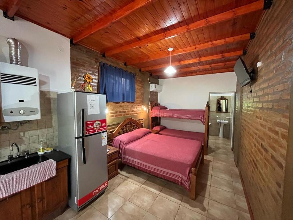 a small kitchen with two beds and a refrigerator at Departamentos La Morita in Embalse
