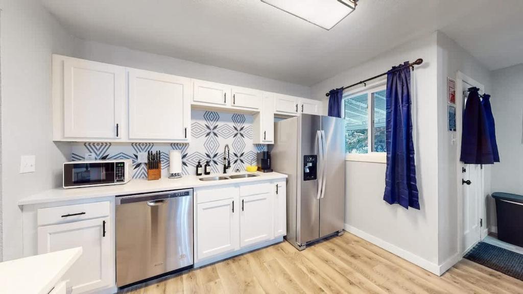 a kitchen with white cabinets and a stainless steel refrigerator at Two bedroom family home near Anschutz Medical in Aurora