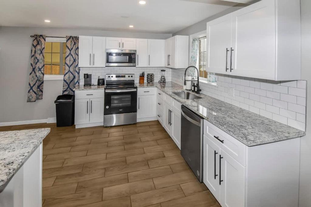 una cucina con mobili bianchi e pavimento in legno di Three bedroom family home with off street parking and fenced yard a Centennial