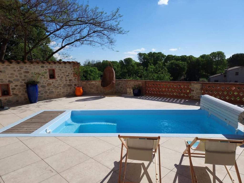 une piscine avec deux chaises et une table dans l'établissement Charmante maison avec piscine proche de la mer, à Sorède