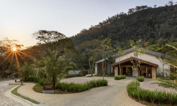 a building with trees and a mountain in the background at Lofts Marambaia in Petrópolis