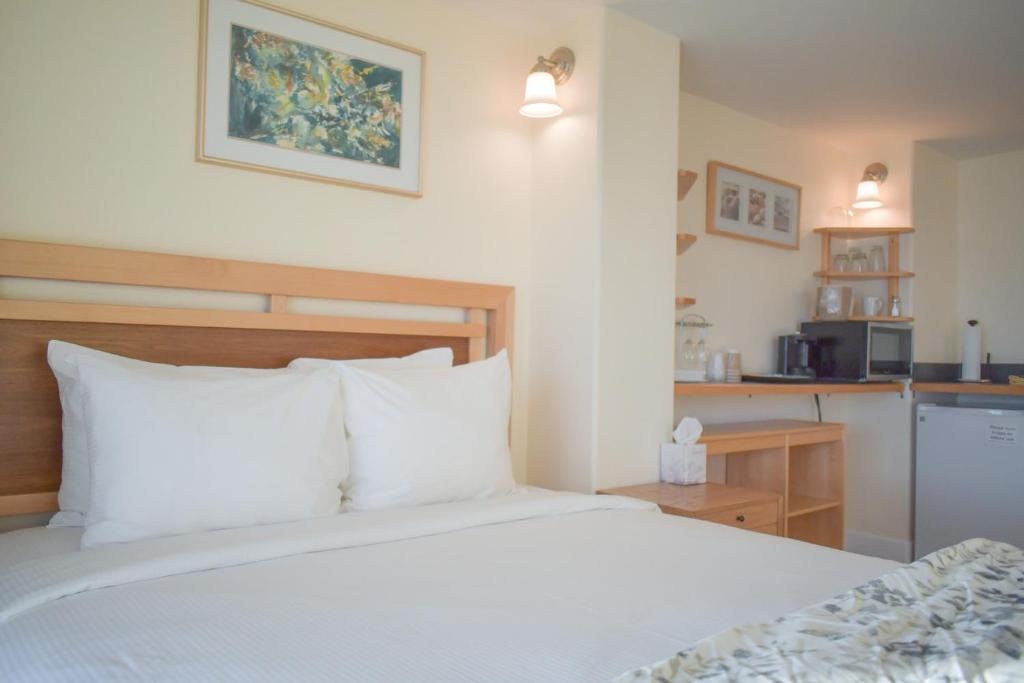 Un dormitorio con una cama blanca y una cocina. en Lakeshore Lodging Lodge 613, en Homer