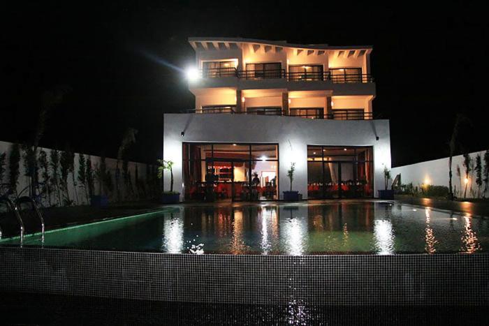 a building with a swimming pool in front of it at night at Auberge Oualidia Dream in Oualidia