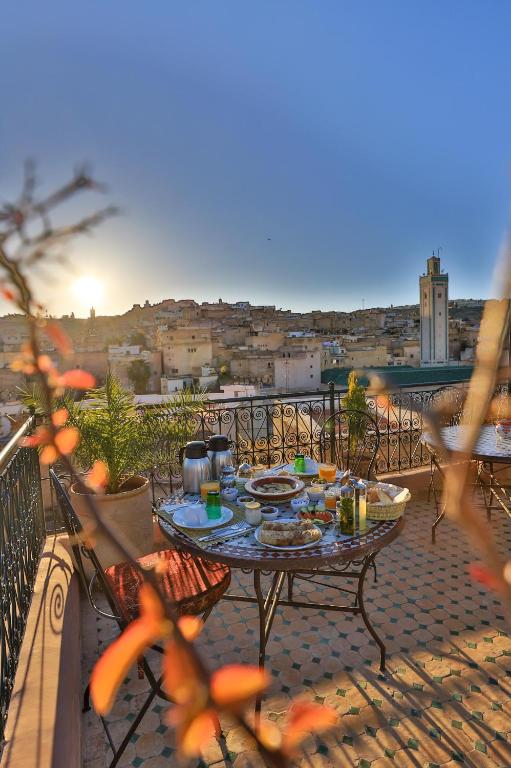 a table on a balcony with a view of a city at Riad Fes la Mama - Rooftop in Fez