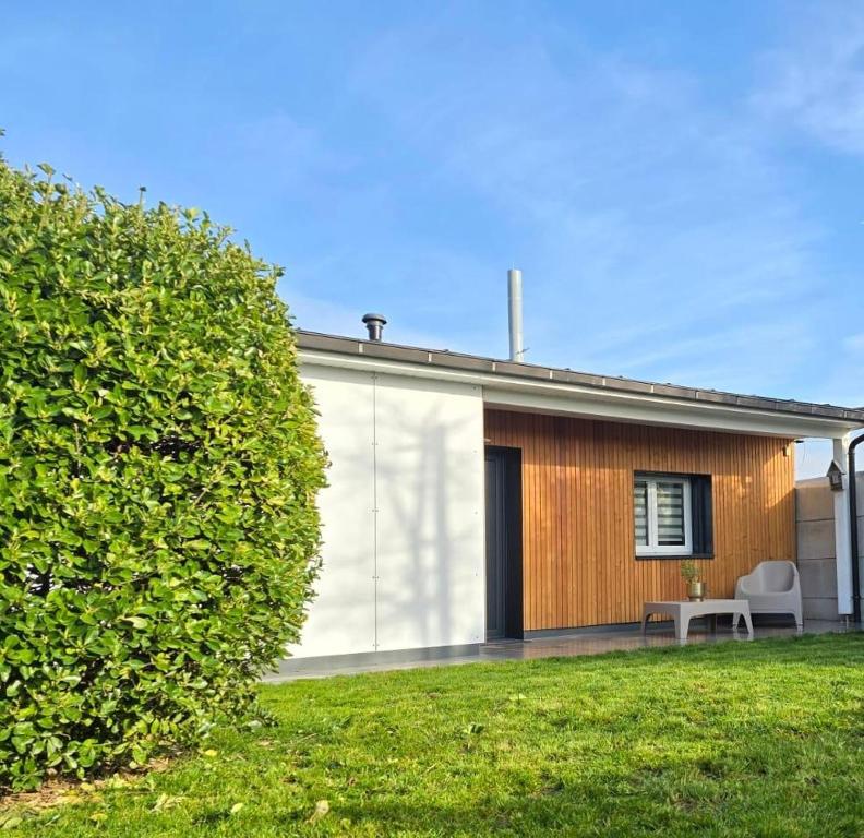une maison avec un grand bush devant elle dans l'établissement Charmante maisonnette individuelle avec jardin et terrasse, à Gargenville