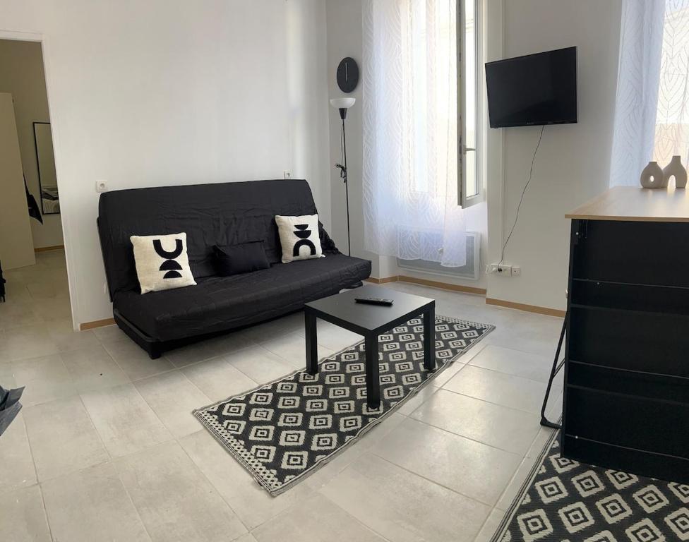 un salon avec un canapé noir et une télévision dans l'établissement T2 cosy, à Marseille
