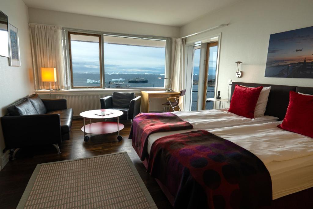 a hotel room with a bed and chairs and a window at Hotel Arctic in Ilulissat