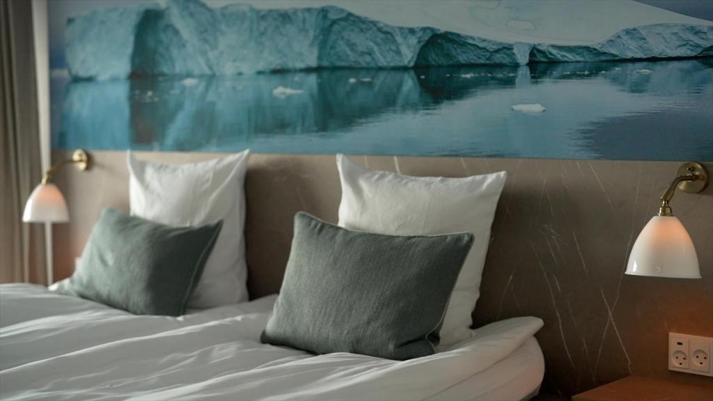 a bedroom with a bed with pillows and a painting at Hotel Arctic in Ilulissat