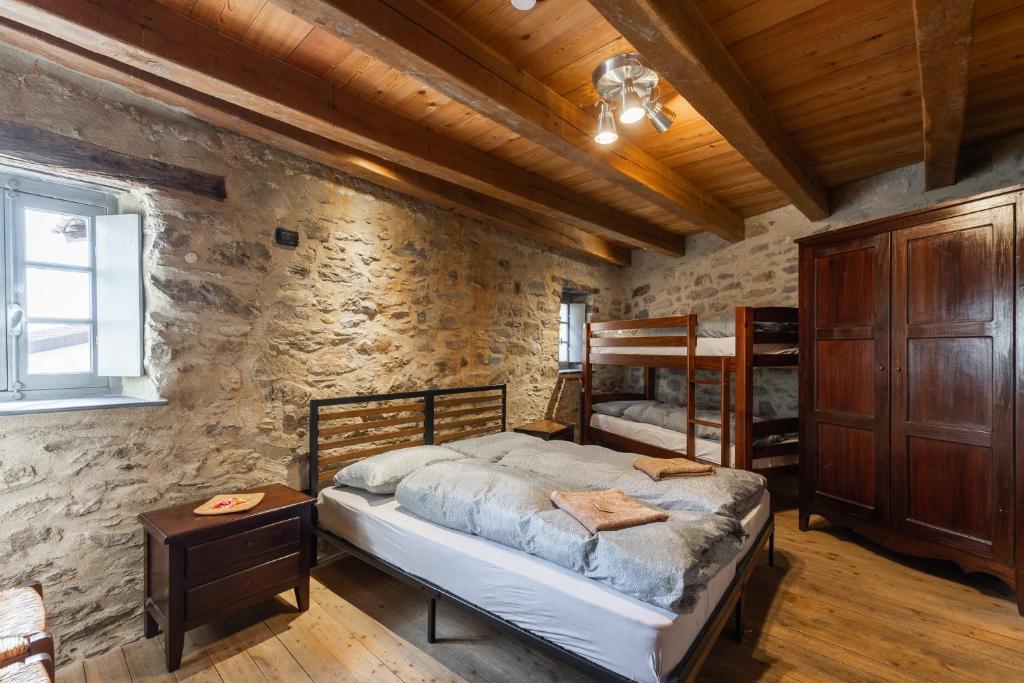 a bedroom with two bunk beds in a stone wall at Rifugio Ca' da Cardella in Mendatica