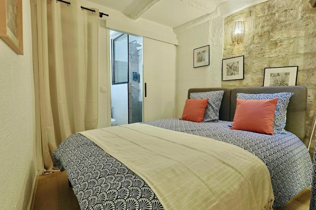 une chambre avec un grand lit avec des oreillers orange dans l'établissement Le Roi - Climatisation à 2 pas de la Gare St Roch, à Montpellier